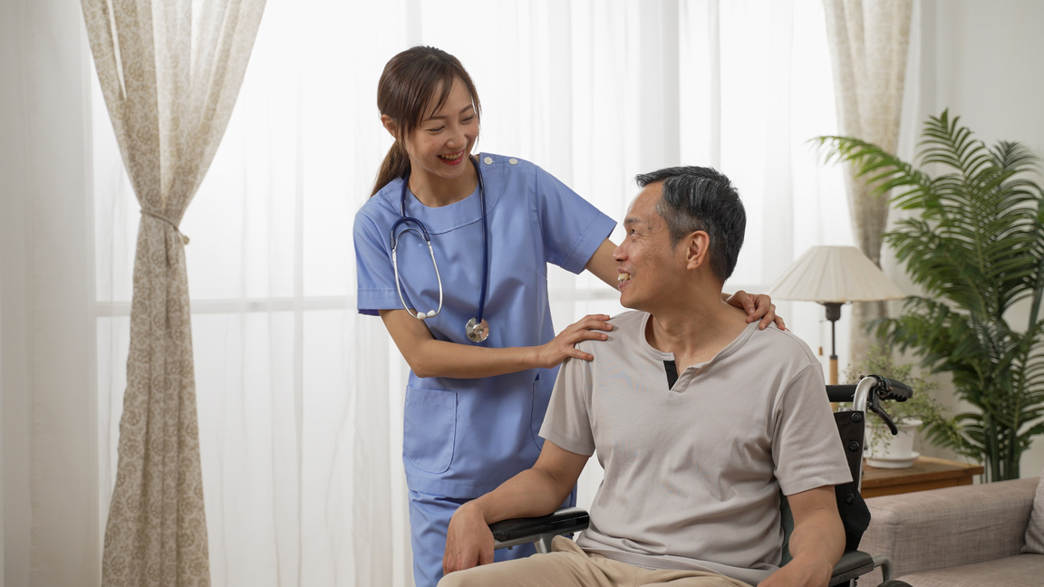 Asian Female Nurse and Male Senior Wheelchair User Enjoying Chat